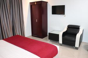 um quarto com uma cama, uma cadeira e uma televisão em Hotel AL Amin em Kuala Lumpur