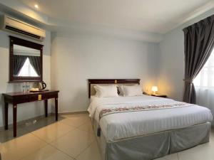 a bedroom with a large bed and a desk at Hotel AL Amin in Kuala Lumpur