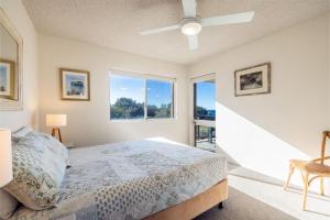 a bedroom with a bed and a large window at Intrepid, 15 3 Intrepid Close - right on the beachfront and WiFi in Shoal Bay