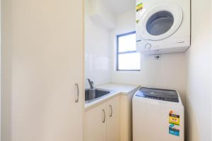 Una pequeña cocina con fregadero y lavadora. en Intrepid, 15 3 Intrepid Close - right on the beachfront and WiFi, en Shoal Bay