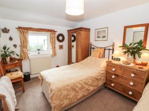 a bedroom with a bed and a dresser and a mirror at Fell Cottage in Wigton