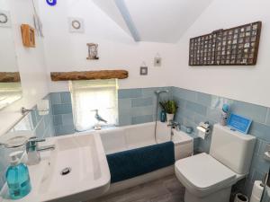a bathroom with a tub and a toilet and a sink at Fell Cottage in Wigton