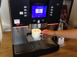 a person is making a cup of coffee in a coffee maker at Ibis Budget Graz City in Graz