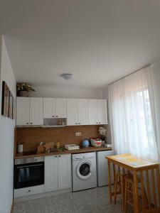 a kitchen with white cabinets and a washing machine at Царево-Студия Нестинарка in Tsarevo