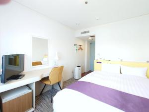 a hotel room with a bed and a desk and a tv at Hotel Montoview Yonezawa in Yonezawa