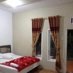 ein Schlafzimmer mit einem Bett und zwei Fenstern in der Unterkunft FAREL HOMESTAY KAWAHIJEN in Banyuwangi