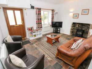 a living room with a leather couch and chairs at No 2 New Cottages in Pembroke