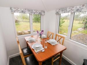 a dining room with a table and two windows at No 2 New Cottages in Pembroke