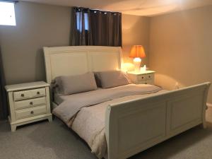 ein Schlafzimmer mit einem weißen Bett und einem Nachttisch mit einer Lampe in der Unterkunft Licensed spacious basement suite with two king size beds in Chilliwack