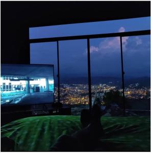 una persona sentada frente a una gran ventana viendo una TV en habitación en Villa Tina, en Santa Rosa de Cabal