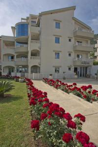una fila di rose rosse davanti a un edificio di Vila V Lux Apartments a Petrovac na Moru