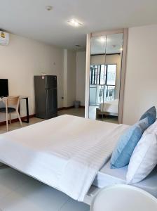 un grande letto bianco con cuscini blu in una stanza di The Lodge @ Min Residence a Bangkok