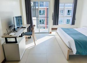 a bedroom with a bed and a desk with a computer at The Lodge @ Min Residence in Bangkok