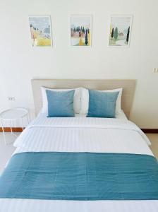 un grande letto con cuscini blu in una camera da letto di The Lodge @ Min Residence a Bangkok