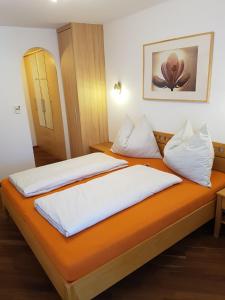 two beds in a room with an orange bedvisor at Appartment Ahorn in Maria Alm am Steinernen Meer