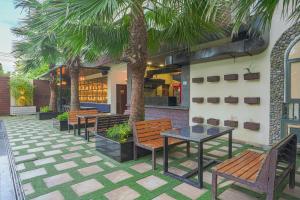 a patio with benches and tables and palm trees at Hotel Escala By Levelup in Amritsar