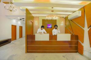 two people standing at a reception desk in a lobby at Hotel Escala By Levelup in Amritsar