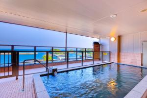 een zwembad in een gebouw met uitzicht op de oceaan bij Hotel Seaside Shimabara in Shimabara