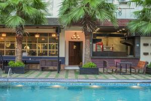 a house with a swimming pool and palm trees at Hotel Escala By Levelup in Amritsar