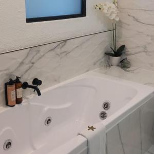 a white bath tub with a mirror and a sink at Orewa Beachcomber in Orewa