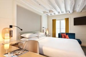 a bedroom with a large white bed and a table at Hotel Opéra Richepanse in Paris