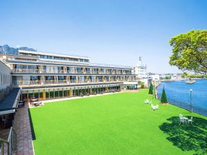 un grand bâtiment avec une pelouse verte en face de l'eau dans l'établissement Hotel Seaside Shimabara, à Shimabara