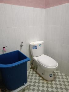 een badkamer met een toilet en een blauwe emmer bij AL IZZAM HOMESTAY in Pagaralam