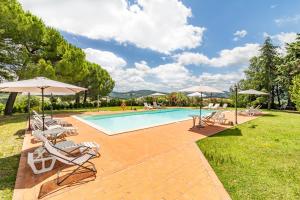 una piscina con tumbonas y sombrillas en Family Apartments With Pool Near Volterra - Happy Rentals, en Pomarance