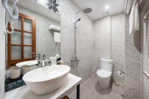 La salle de bains est pourvue d'un grand lavabo blanc et de toilettes. dans l'établissement Le Parfum Apartment and Hotel, à Hanoï