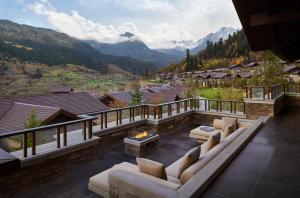 a patio with couches and a fireplace and mountains at Rissai Valley, a Ritz-Carlton Reserve in Jiuzhaigou