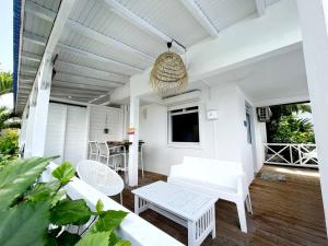 eine Veranda mit weißen Möbeln und einem Kronleuchter in der Unterkunft La Belle Vue - Grand studio vues mer et accès plages in Deshaies
