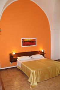 1 dormitorio con 1 cama con pared de color naranja en B&B Masseria Donna Carlotta, en Serrano