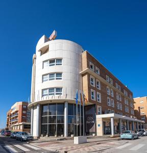 un edificio en una calle con coches aparcados delante en Hotel Bartos, en Almussafes