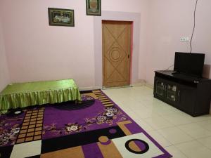 een kamer met een deur, een tapijt en een tv bij AL IZZAM HOMESTAY in Pagaralam