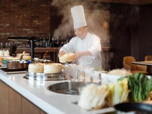 ein Koch steht in einer Küche und bereitet Essen zu in der Unterkunft Sheraton Nanchang Hotel in Nanchang