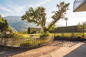 a fence with a tree and mountains in the background at Casa Vacanze Salirai in Ponte in Valtellina