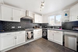 a kitchen with white cabinets and a washer and dryer at Ashford Home - Spacious house close to Ashford International and free drive parking and hot tub in Ashford