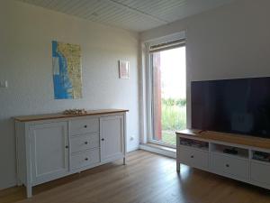 a living room with a flat screen tv and a large window at Wattschnecke in Bohmstedt