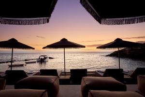 een strand met stoelen en parasols en een boot in het water bij SEA ZANTE Luxury Beachfront Retreat in Tragaki