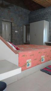 a large bed in a room with a stone wall at Vamoose Hampi Homestay Otters Island in Hampi