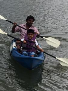een man en een kind in een kano op het water bij Vamoose Hampi Homestay Otters Island in Hampi