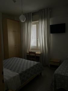 um quarto com 2 camas, uma secretária e uma janela em Hotel Annita Cervia em Cervia