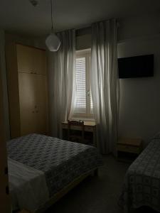 a bedroom with two beds and a desk and a window at Hotel Annita Cervia in Cervia