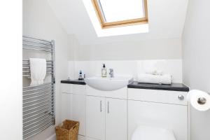 a white bathroom with a sink and a mirror at Woodfield Wellbeing in Oving