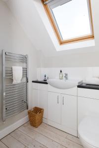 a white bathroom with a sink and a window at Woodfield Wellbeing in Oving