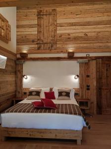 een slaapkamer met houten wanden en een bed met rode kussens bij Firnelicht in Gressoney-Saint-Jean +19 foto's
