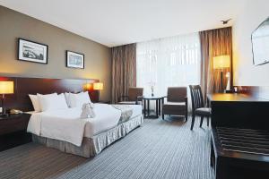 コタキナバルにあるホテル シックスティ3の大型ベッドとピアノが備わるホテルルームです。