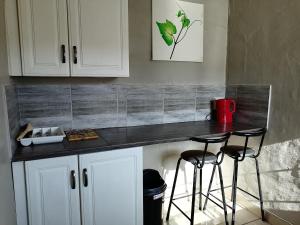 a kitchen with a counter and two stools at a table at The Private and Cosy Guest House 2 in Germiston