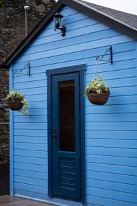 un cobertizo azul con dos cestas y una puerta en West Wicklow Glamping with Hot Tub, en Baltinglass