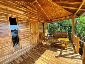 une terrasse en bois avec un banc et une table dans l'établissement Kaloka Airport Hotel, à Labu Sumbawa
